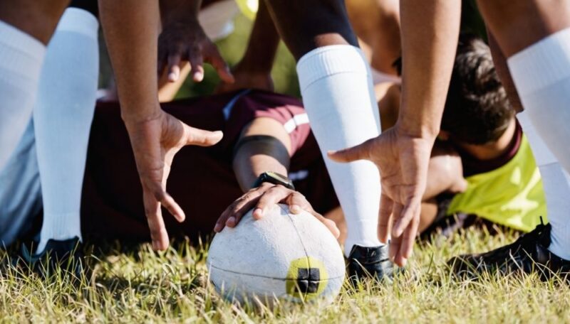 Ragbi igrači okupljeni oko lopte spremni za početak akcije na terenu